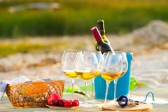 Vidrios del vino blanco en la playa en la puesta del sol, tema de la comida campestre, foto de archivo libre de regalías Vidrios del vino blanco en la playa en la puesta del sol, tema de la comida campestre, foto de archivo libre de regalías