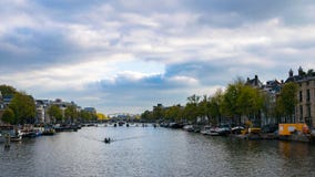Vie di Amsterdam con la barca sull'acqua e sul cielo fotografie stock libere da diritti Vie di Amsterdam con la barca sull'acqua e sul cielo fotografie stock libere da diritti