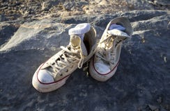 Vieilles chaussures sur une roche images stock Vieilles chaussures sur une roche images stock