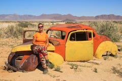 Vieilles voitures rouillées abandonnées dans le désert de la Namibie et une fille de touristes blanche dodue près du parc nationa photographie stock Vieilles voitures rouillées abandonnées dans le désert de la Namibie et une fille de touristes blanche dodue près du parc nationa photographie stock