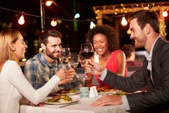 Vier Freunde, die Abendessen am Dachspitzenrestaurant essen lizenzfreie stockfotos Vier Freunde, die Abendessen am Dachspitzenrestaurant essen lizenzfreie stockfotos