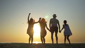 Vier Freunde, die auf den Strand bei Sonnenuntergang in der Zeitlupe springen stock footage Vier Freunde, die auf den Strand bei Sonnenuntergang in der Zeitlupe springen stock footage