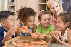 Vier Kinder zuhause mit der Frau, die Pizza isst stockfotografie Vier Kinder zuhause mit der Frau, die Pizza isst stockfotografie