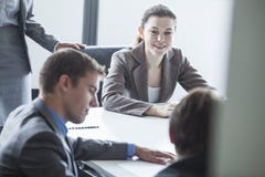 Vier lächelnde Geschäftsleute, die an einem Tisch sitzen und ein Geschäftstreffen im Büro haben stockfotografie Vier lächelnde Geschäftsleute, die an einem Tisch sitzen und ein Geschäftstreffen im Büro haben stockfotografie