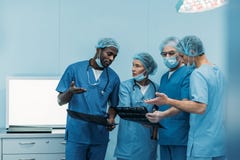vier multi-etnische chirurgen die over geduldige röntgenstraal spreken royalty-vrije stock afbeelding vier multi-etnische chirurgen die over geduldige röntgenstraal spreken royalty-vrije stock afbeelding