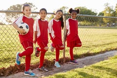 Vier vor jugendlich Mädchen in einem Fußballteam, das zur Kamera schaut stockfotografie Vier vor jugendlich Mädchen in einem Fußballteam, das zur Kamera schaut stockfotografie
