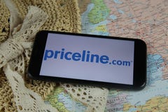 Closeup of mobile phone screen wit logo lettering of online booking travel agency priceline.com with sun hat and map