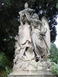 Vieux monument, ange de couvée sur un piédestal avec des fleurs et une ancre flottante images stock Vieux monument, ange de couvée sur un piédestal avec des fleurs et une ancre flottante images stock