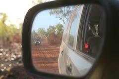 View of four wheel drive vehicle behind in the rear mirror along a red, corrugated, dusty road in Australia stock photography View of four wheel drive vehicle behind in the rear mirror along a red, corrugated, dusty road in Australia stock photography