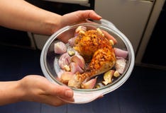View of a glass tray with a baked chicken drumstick marinated with pieces of onion and garlic