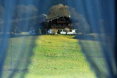 Small house at the mountain seen through the curtains of my window