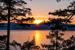 View of the picturesque lake through the trees at sunset. View of the scenic lake through the trees at sunset