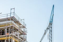Scaffolding around the shell of a house with sky and crane in the background stock photo Scaffolding around the shell of a house with sky and crane in the background stock photo