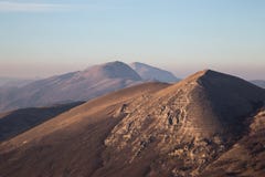 A view of some mountains top, beneath an empty blue sky at golden hour royalty free stock photo A view of some mountains top, beneath an empty blue sky at golden hour royalty free stock photo
