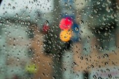 View traffic lights through the wet glass of the car.