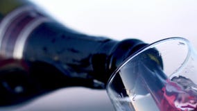 Vin rouge versant dans la vue en verre d'angle faible dans le mouvement lent r Vin rouge versant dans la vue en verre d'angle faible dans le mouvement lent r