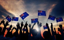 Vinkande australierflaggor för grupp människor i tillbaka Lit royaltyfri fotografi Vinkande australierflaggor för grupp människor i tillbaka Lit royaltyfri fotografi