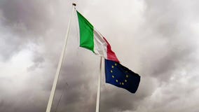 Vinkande tygtextur av flaggan av Italien och fackliga Europa p? himmel med moln, begrepp av Vinkande tygtextur av flaggan av Italien och fackliga Europa p? himmel med moln, begrepp av