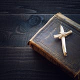 Vintage Christian Leather Bible Still Life with Cross made of grass reeds on Dark Wood Board Background. Square