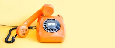 Vintage phone busy handset receiver on yellow background. Retro style orange telephone communication call center concept