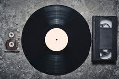 Vinyl Record, Audio And Video Cassettes On A Gray Concrete Surface. Retro Media Technology From The 80s. Top View. Stock Photos