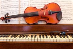 Violin and Piano With Music. An old wooden piano sits with a violin, bow, and sheet music Violin and Piano With Music. An old wooden piano sits with a violin, bow, and sheet music