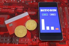 Virtuelle Münzen, bitcoins auf Plastikkreditkarte Smartphone mit dem bitcoin Bargeld-Handelsdiagramm Bildschirm Entwurf auf einem stockbild Virtuelle Münzen, bitcoins auf Plastikkreditkarte Smartphone mit dem bitcoin Bargeld-Handelsdiagramm Bildschirm Entwurf auf einem stockbild
