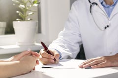 Visita medica - medico e paziente che si siedono dalla tavola immagine stock libera da diritti Visita medica - medico e paziente che si siedono dalla tavola immagine stock libera da diritti