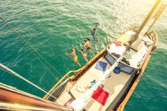 Vista aerea di giovani amici che saltano dalla barca a vela sul mare fotografia stock Vista aerea di giovani amici che saltano dalla barca a vela sul mare fotografia stock