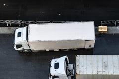 Vista aerea/sopraelevata di due 6 camion di consegna bianchi del carraio parcheggiati parallelamente sulla strada asfaltata immagine stock libera da diritti Vista aerea/sopraelevata di due 6 camion di consegna bianchi del carraio parcheggiati parallelamente sulla strada asfaltata immagine stock libera da diritti