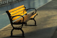 Vista aislada de un banco de madera de la calle del ironcast debajo del sol de la mañana con un carril de bicicleta en el fondo imágenes de archivo libres de regalías Vista aislada de un banco de madera de la calle del ironcast debajo del sol de la mañana con un carril de bicicleta en el fondo imágenes de archivo libres de regalías
