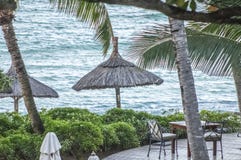 Vista ao mar sobre o decking com tabela e as cadeiras com guarda-chuvas da palha fotografia de stock Vista ao mar sobre o decking com tabela e as cadeiras com guarda-chuvas da palha fotografia de stock