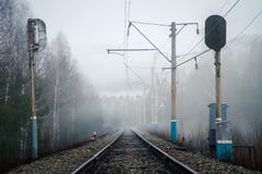 Vista del ferrocarril, de los semáforos y de los polos eléctricos en niebla en primavera foto de archivo libre de regalías Vista del ferrocarril, de los semáforos y de los polos eléctricos en niebla en primavera foto de archivo libre de regalías