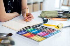 Vista di angolo del primo piano di un progetto femminile del disegno del pittore allo sketchbook facendo uso della matita Artista immagini stock libere da diritti Vista di angolo del primo piano di un progetto femminile del disegno del pittore allo sketchbook facendo uso della matita Artista immagini stock libere da diritti