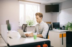 Vista dos homens de funcionamento no escritório Desenhista à moda no assento do trabalho Centrado sobre seu trabalho Imagem de Stock Royalty Free Vista dos homens de funcionamento no escritório Desenhista à moda no assento do trabalho Centrado sobre seu trabalho Imagem de Stock Royalty Free