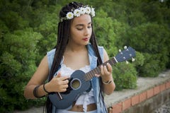 Vista frontale di giovane bella ragazza con capelli intrecciati, giocante le ukulele fotografia stock Vista frontale di giovane bella ragazza con capelli intrecciati, giocante le ukulele fotografia stock