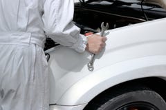 Vista laterale del meccanico automobilistico in uniforme con la chiave che diagnostica motore sotto il cappuccio dell'automobile fotografia stock libera da diritti Vista laterale del meccanico automobilistico in uniforme con la chiave che diagnostica motore sotto il cappuccio dell'automobile fotografia stock libera da diritti