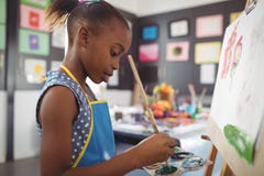 Vista laterale della pittura messa a fuoco della ragazza sulla tela fotografia stock libera da diritti Vista laterale della pittura messa a fuoco della ragazza sulla tela fotografia stock libera da diritti