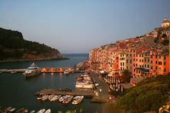 Vista no alvorecer de Portovenere e de porto com barcos amarrados, mar, construções coloridas, árvores imagens de stock Vista no alvorecer de Portovenere e de porto com barcos amarrados, mar, construções coloridas, árvores imagens de stock