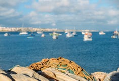Vista sui precedenti, fuoco selettivo delle reti da pesca, del mare e del villaggio - catturato in Cascais, Portogallo Fotografie Stock Libere da Diritti Vista sui precedenti, fuoco selettivo delle reti da pesca, del mare e del villaggio - catturato in Cascais, Portogallo Fotografie Stock Libere da Diritti