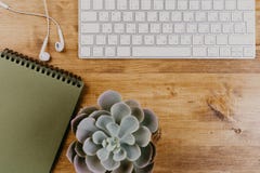 Vista superior del escritorio de oficina de madera de moda con el teclado, los auriculares blancos y los materiales de oficina imagen de archivo Vista superior del escritorio de oficina de madera de moda con el teclado, los auriculares blancos y los materiales de oficina imagen de archivo