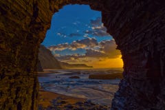 Visualizzazione al tramonto del mare dall'interno di una caverna alla spiaggia di Barriga, porta Immagini Stock Visualizzazione al tramonto del mare dall'interno di una caverna alla spiaggia di Barriga, porta Immagini Stock
