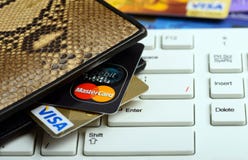 Visum och mastercard kreditkortar i plånbok över den keyboar anteckningsboken arkivbild Visum och mastercard kreditkortar i plånbok över den keyboar anteckningsboken arkivbild