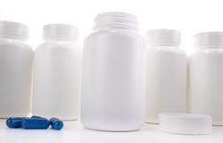 Vit preventivpillerflaska som är öppen på räknare mellan locket och blåttpreventivpillerar arkivbilder Vit preventivpillerflaska som är öppen på räknare mellan locket och blåttpreventivpillerar arkivbilder