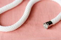 Vit prydd med p?rlor halsband p? en f?rg f?r textilbakgrundskorall arkivbild Vit prydd med p?rlor halsband p? en f?rg f?r textilbakgrundskorall arkivbild