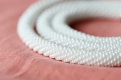 Vit prydd med p?rlor halsband p? en f?rg f?r textilbakgrundskorall royaltyfri bild Vit prydd med p?rlor halsband p? en f?rg f?r textilbakgrundskorall royaltyfri bild