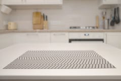 Vit tabell med en servett på bakgrunden av ett suddigt kök royaltyfri bild Vit tabell med en servett på bakgrunden av ett suddigt kök royaltyfri bild