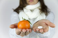 Vitamine da frutta o dalle droghe? Una giovane donna malata con una sciarpa sul suo collo mostra un mandarino nella sua mano dest fotografia stock Vitamine da frutta o dalle droghe? Una giovane donna malata con una sciarpa sul suo collo mostra un mandarino nella sua mano dest fotografia stock