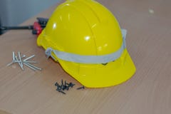 Vite gialla del rilascio del cappello di sicurezza disposta su una tavola di legno immagine stock Vite gialla del rilascio del cappello di sicurezza disposta su una tavola di legno immagine stock
