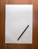 Vitt ark av papper med en blyertspenna på en träbakgrund Arkivbild Vitt ark av papper med en blyertspenna på en träbakgrund Arkivbild